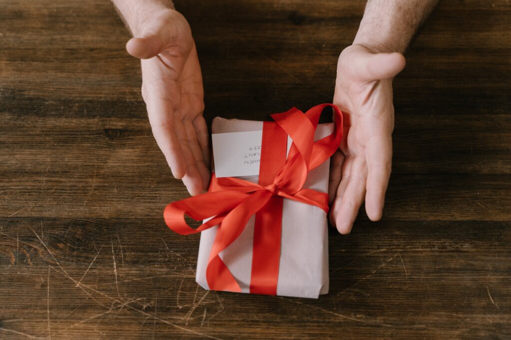 a person holding a gift with red ribbon