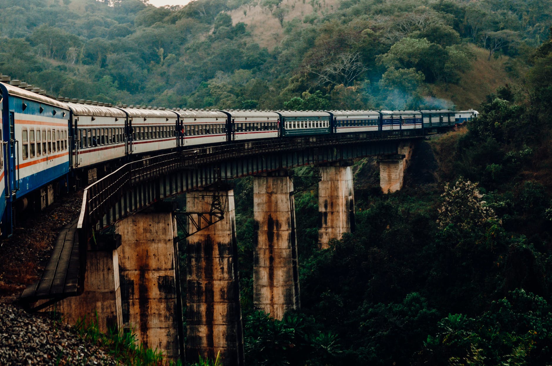 train driving on bridge over river against ridge